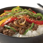 Beautifully plated Beef and Pepper Rice Bowl with colorful bell peppers, tender beef, and rice, garnished with green onions and sesame seeds.