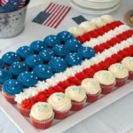 Cupcake cake arranged in the shape of the American flag with red, white, and blue frosting, decorated with stars and patriotic 4th of July accents.