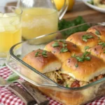 BBQ chicken sliders made with shredded chicken, melted cheese, and soft buns, brushed with garlic butter and baked until golden, served in a tray with picnic-themed decor.